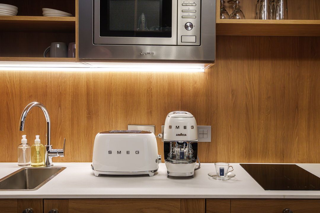 Kitchen countertop with a toaster, espresso machine, and sink, below a microwave and wooden cabinets.