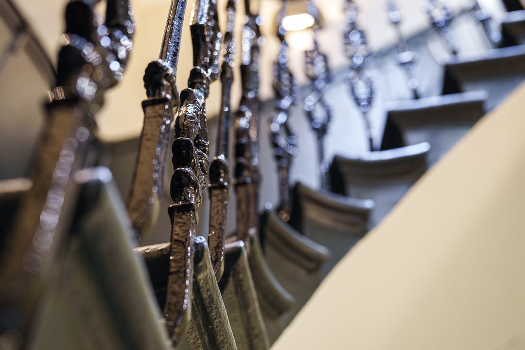 Close-up of a decorative wrought-iron staircase railing with detailed balusters, leading upwards.