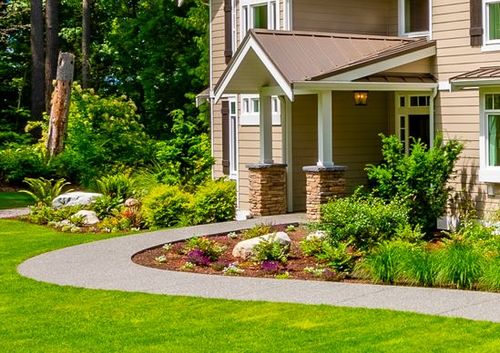 Landscaped front yard with curved walkway and porch on a beige house