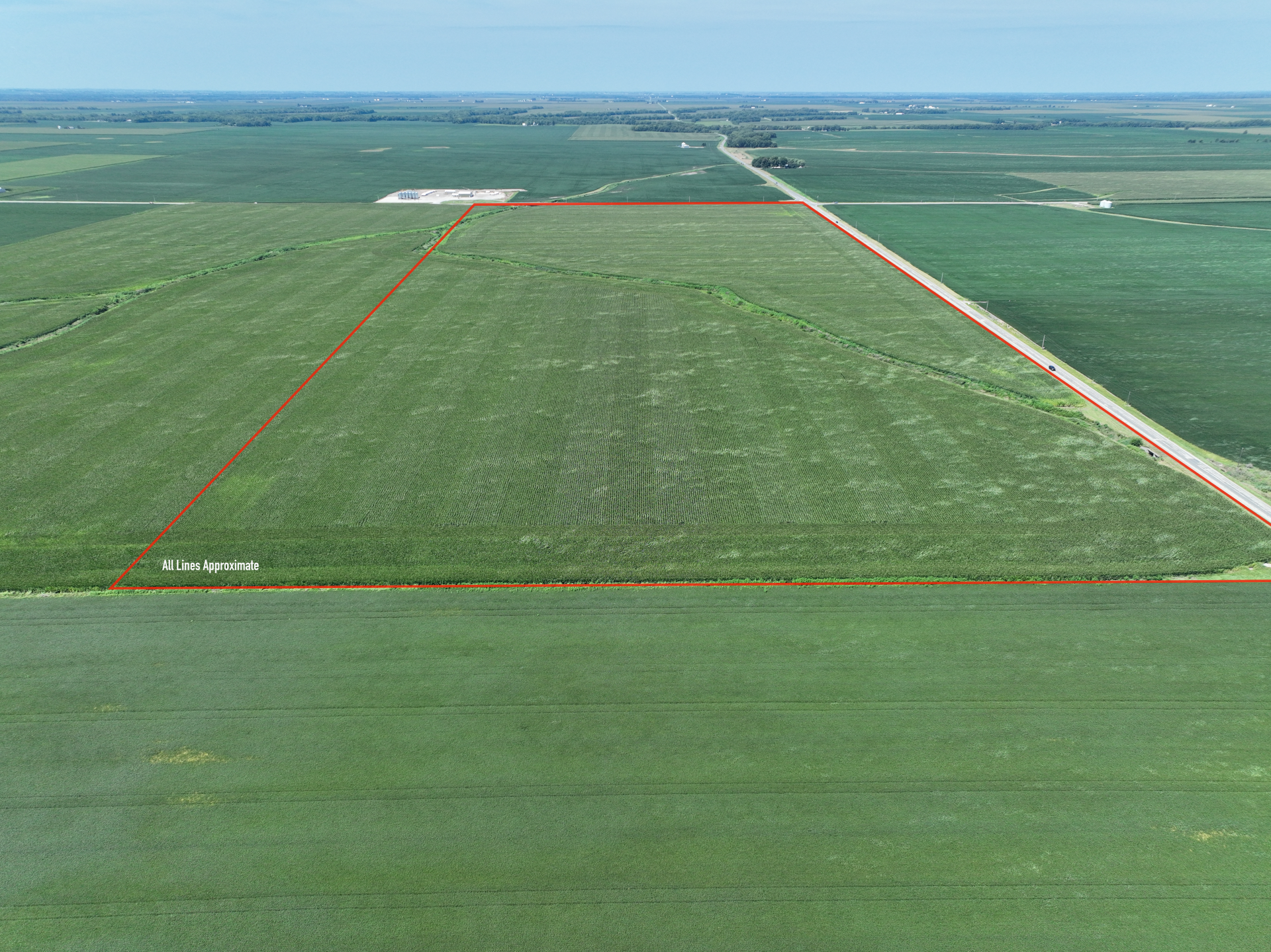 Aerial view of green farmland with a red boundary outlining a large rectangular field
