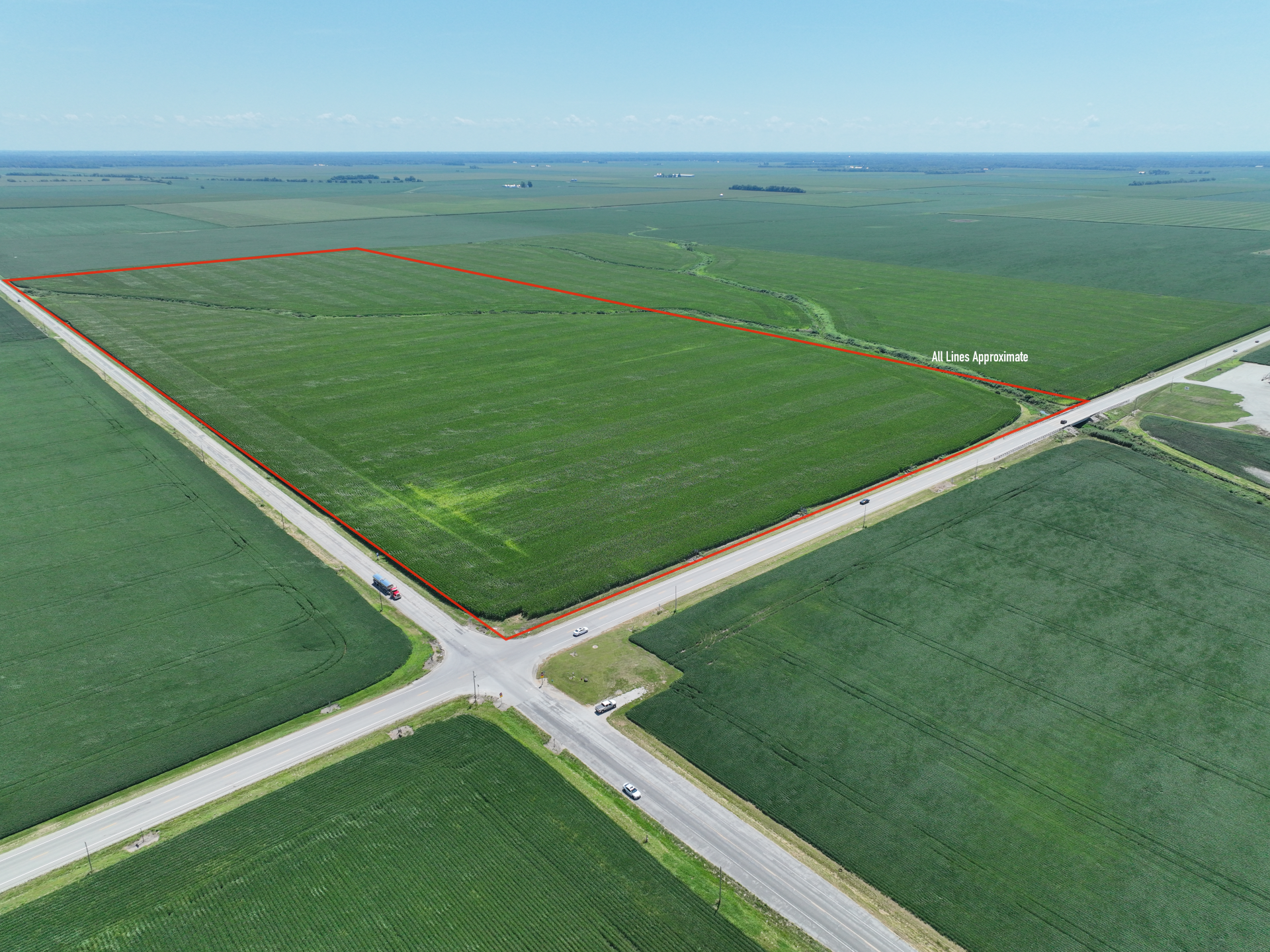 Aerial view of a large green farm field bordered by roads and outlined in red.