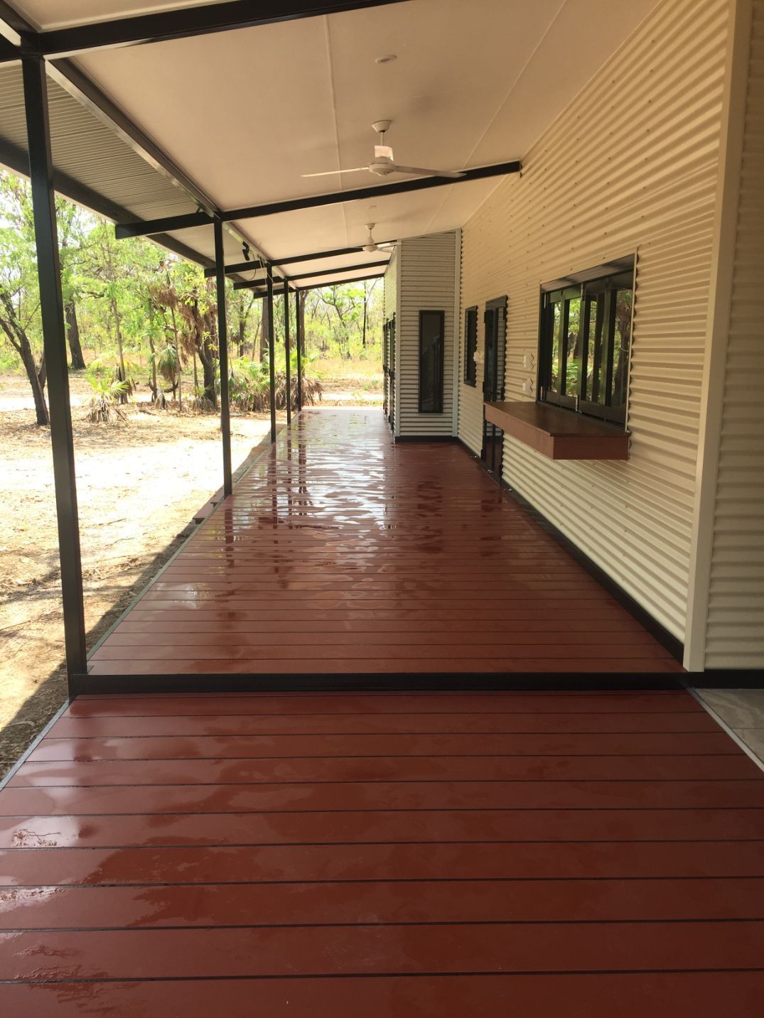 A long red wooden porch with a white building in the background — Local Builders in Yarrawonga, NT