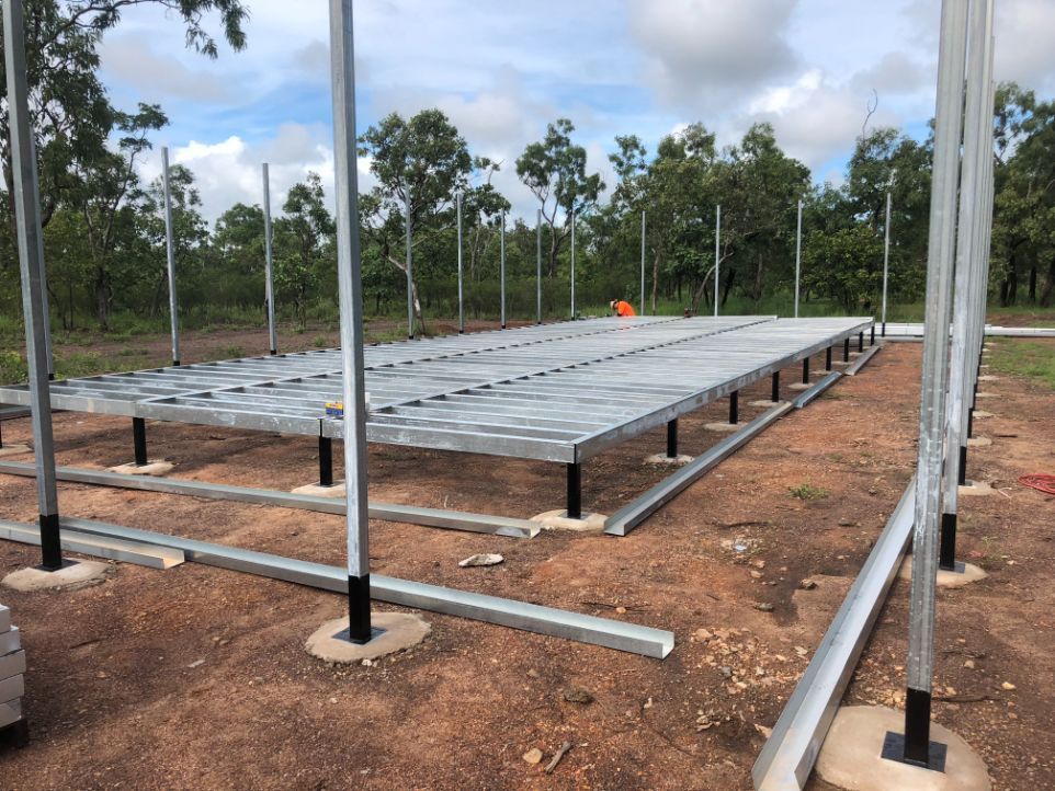 A large metal structure is being built in the middle of a dirt field — Local Builders in Yarrawonga, NT