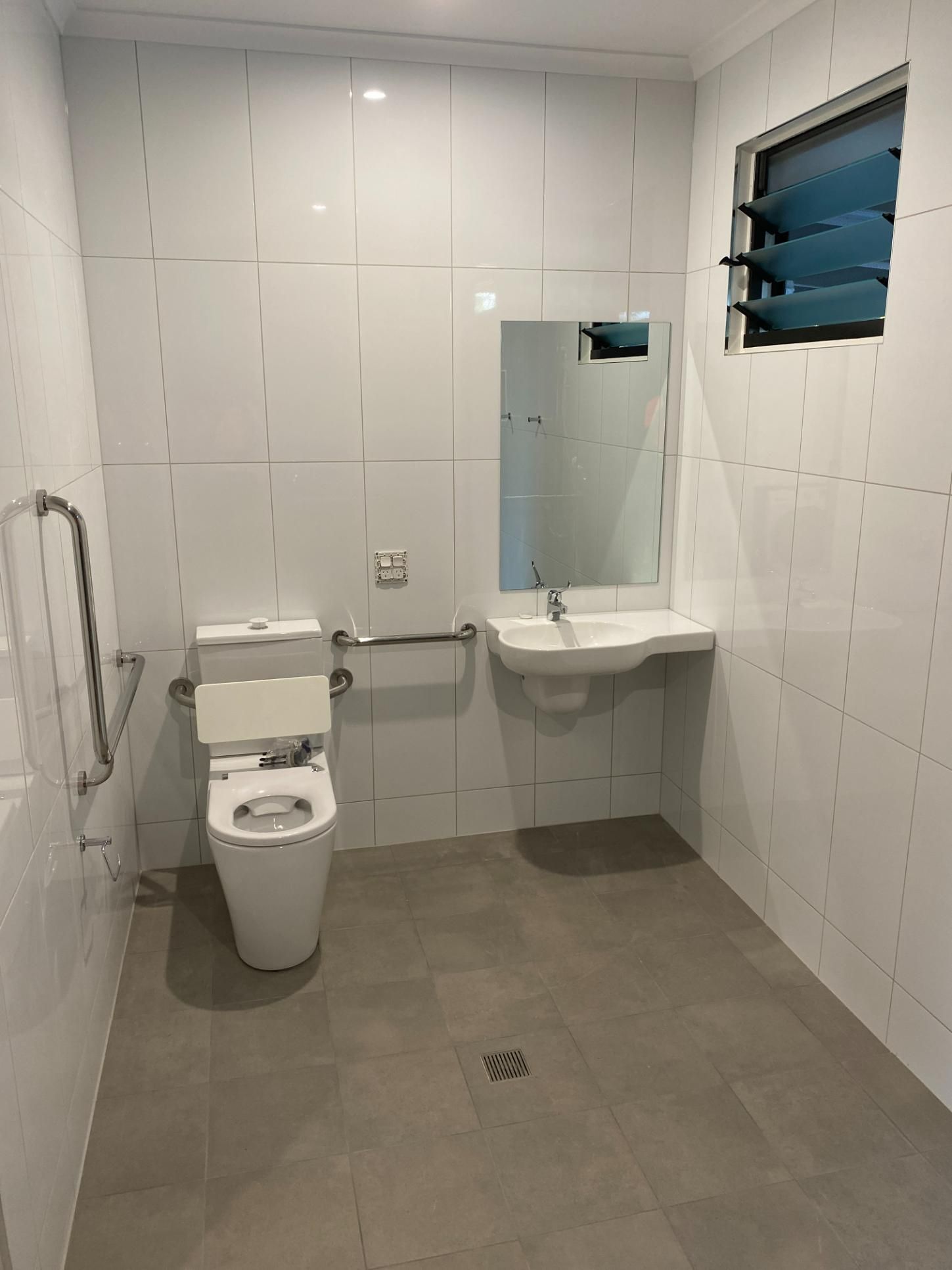 A Bathroom With a Toilet , Sink and Mirror — Local Builders in Yarrawonga, NT