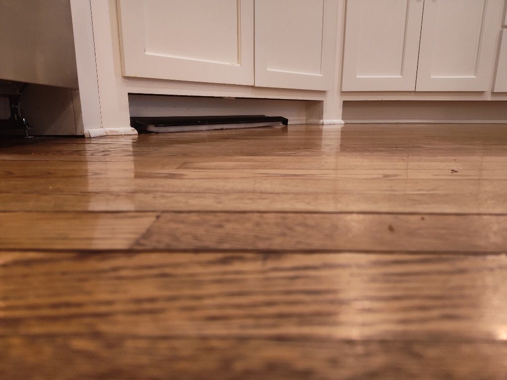 A wooden floor in a kitchen with white cabinets