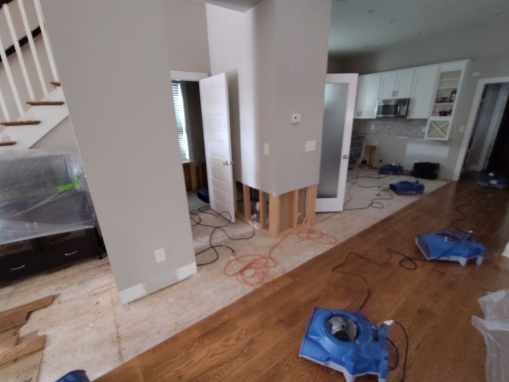 A room with hardwood floors and a staircase in the background