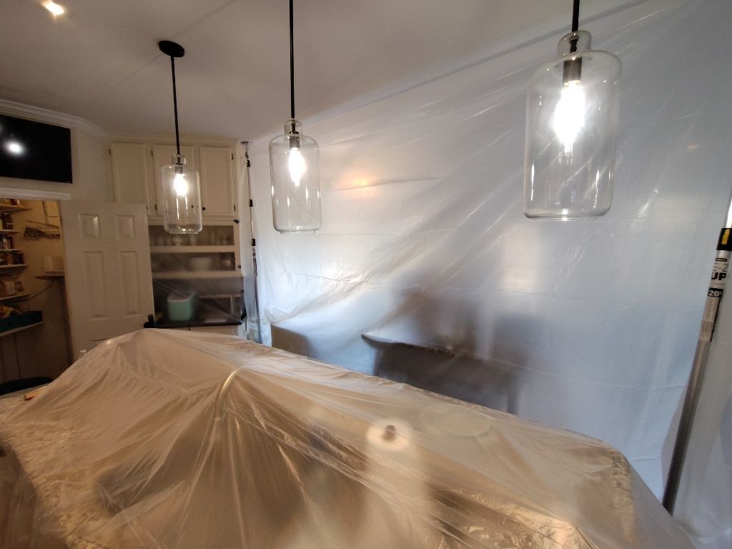 A kitchen is covered in plastic while being painted.