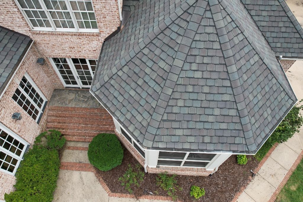 An aerial view of a large brick house with a gray roof.