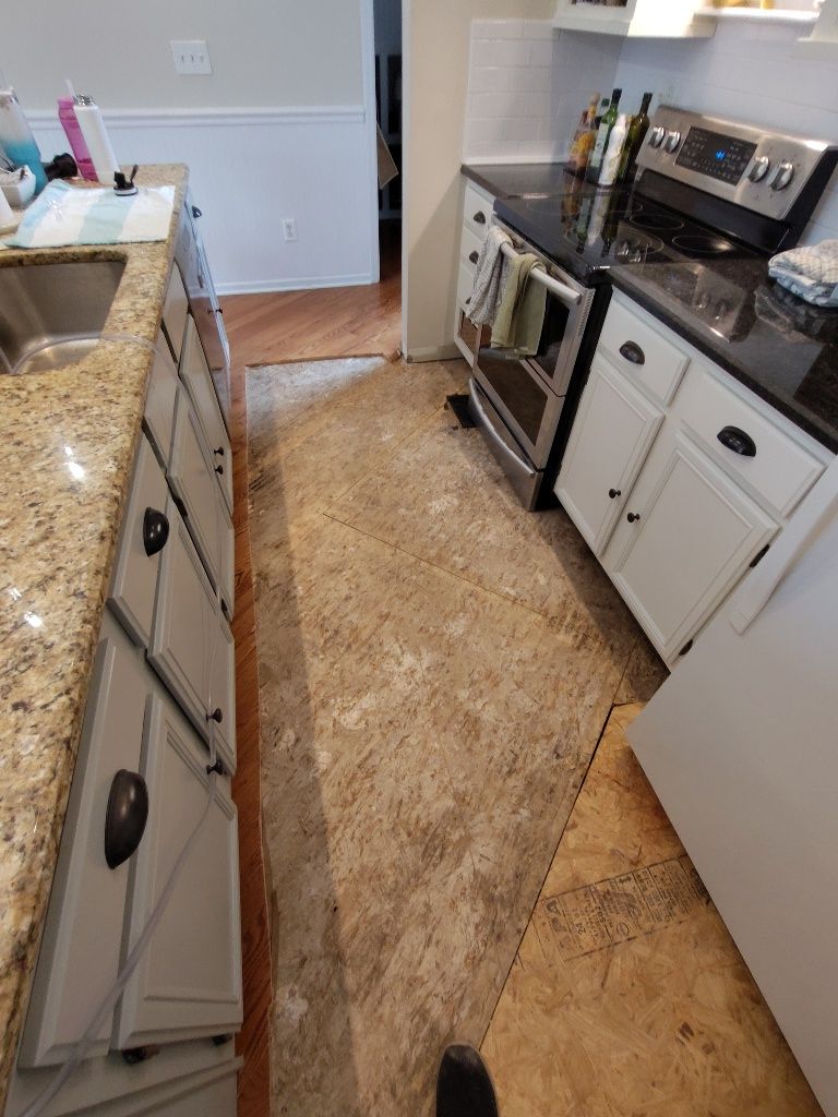 A kitchen with white cabinets , a stove , a sink and a refrigerator.