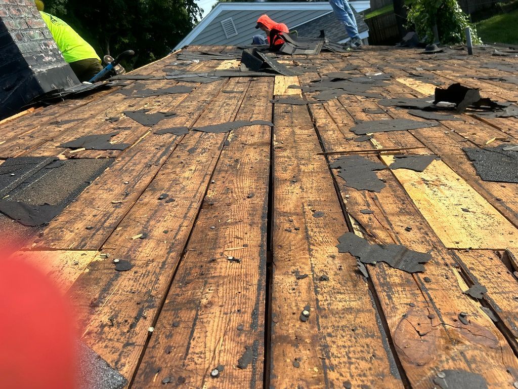 A close up of a wooden deck with a roof in the background.