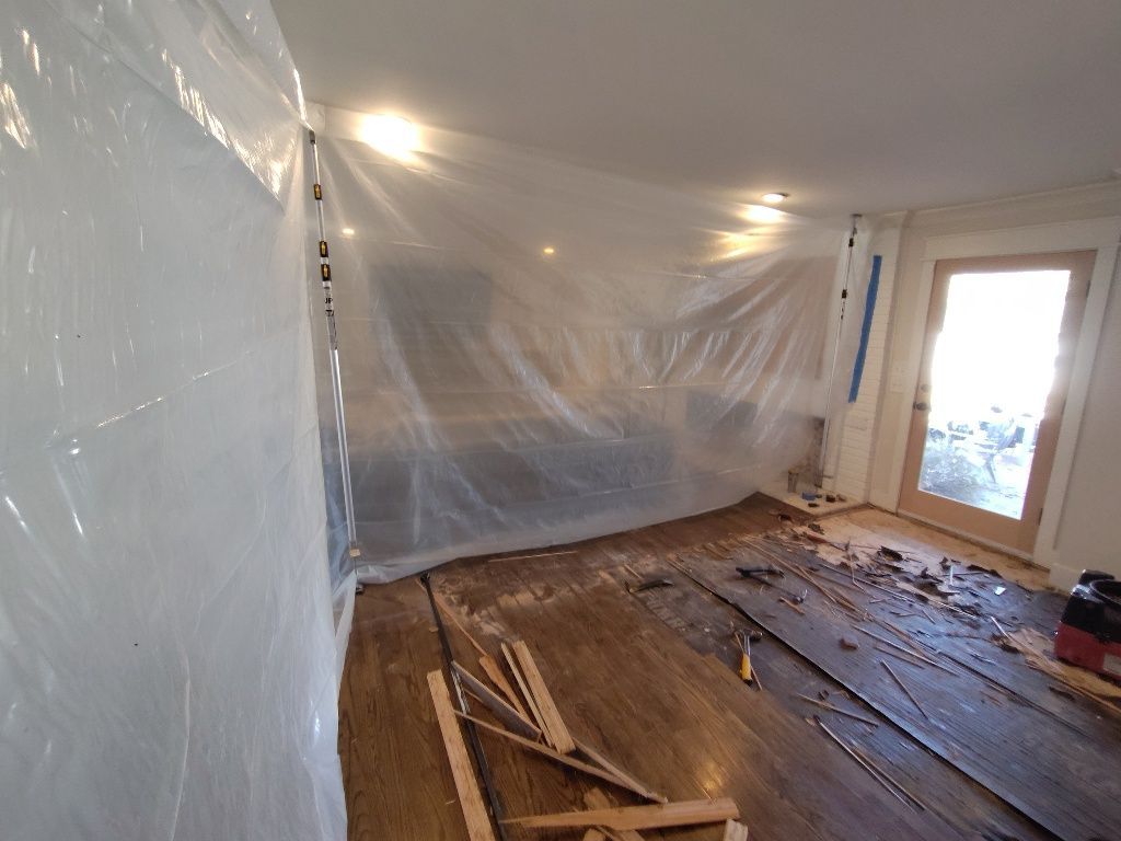 A room with a plastic sheet on the wall and a wooden floor.