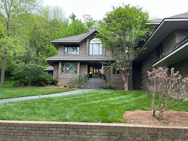 A large brick house with a lush green lawn in front of it.