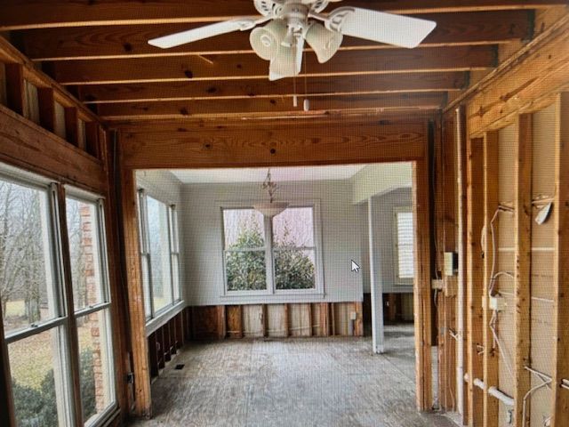 An empty room with a ceiling fan and a lot of windows.