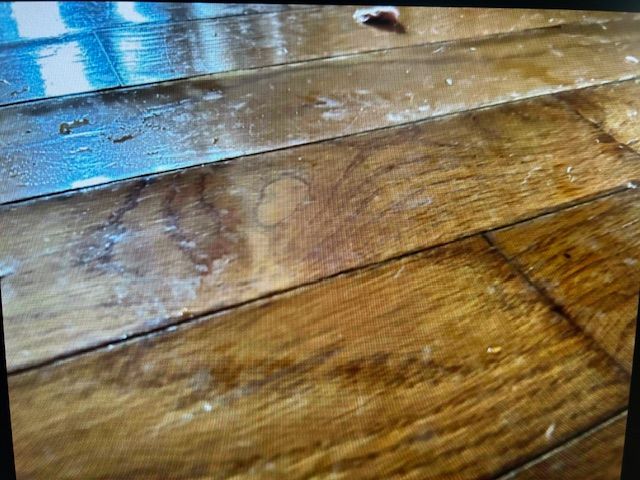 A close up of a wooden floor with water drops on it.