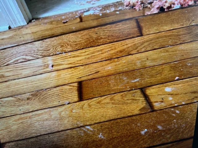 A close up of a wooden floor with a lot of stains on it.