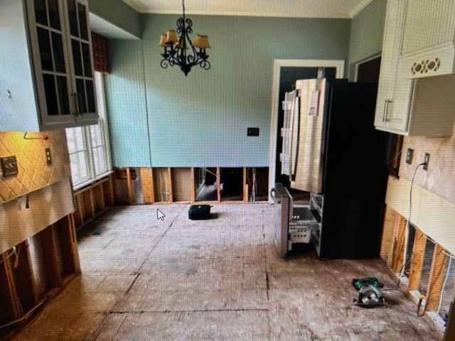 A kitchen with a refrigerator and a chandelier hanging from the ceiling.