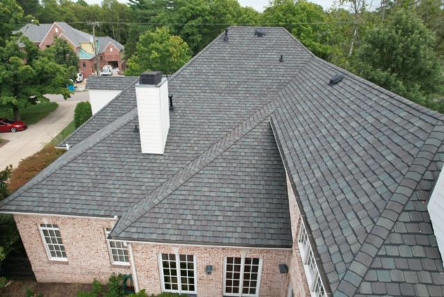 An aerial view of a large brick house with a gray roof.
