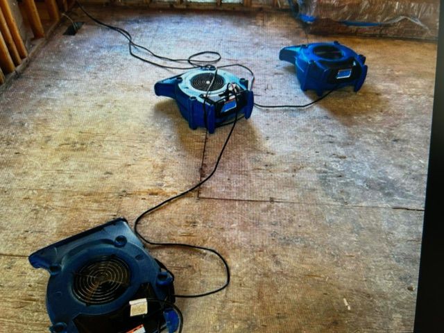 Two blue fans are sitting on a wooden floor.