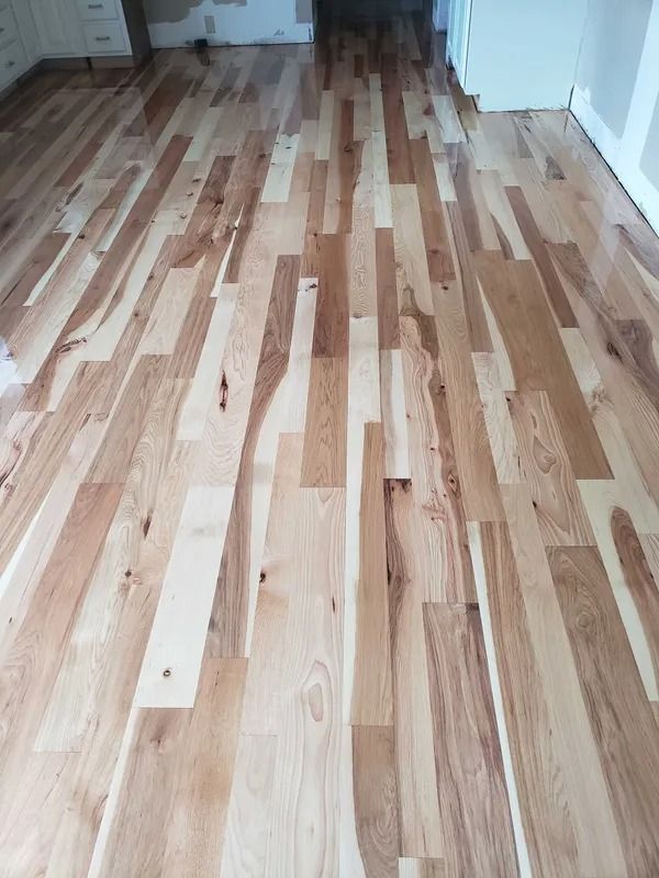 Light wood plank floor in a narrow hallway with white walls and doorways on both sides
