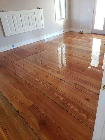 Shiny wooden floor in an empty room with white walls and a radiator
