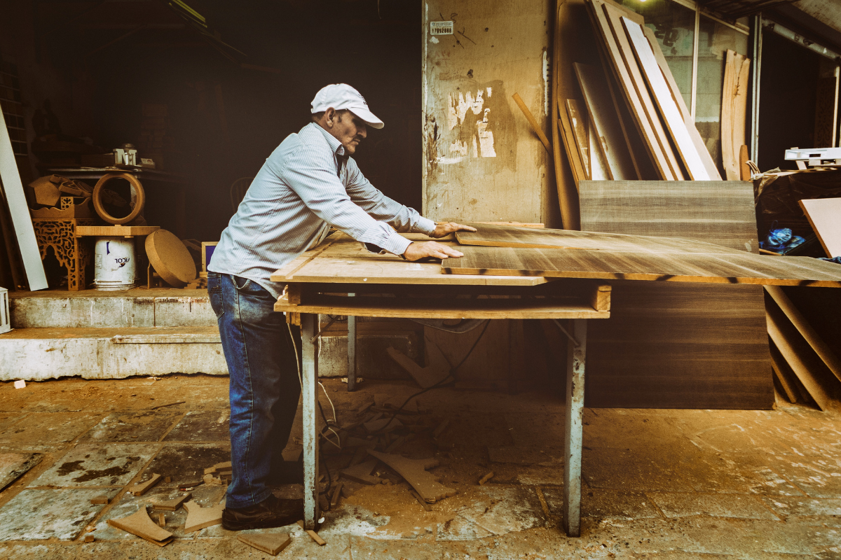 A man is cutting a piece of wood on a table.