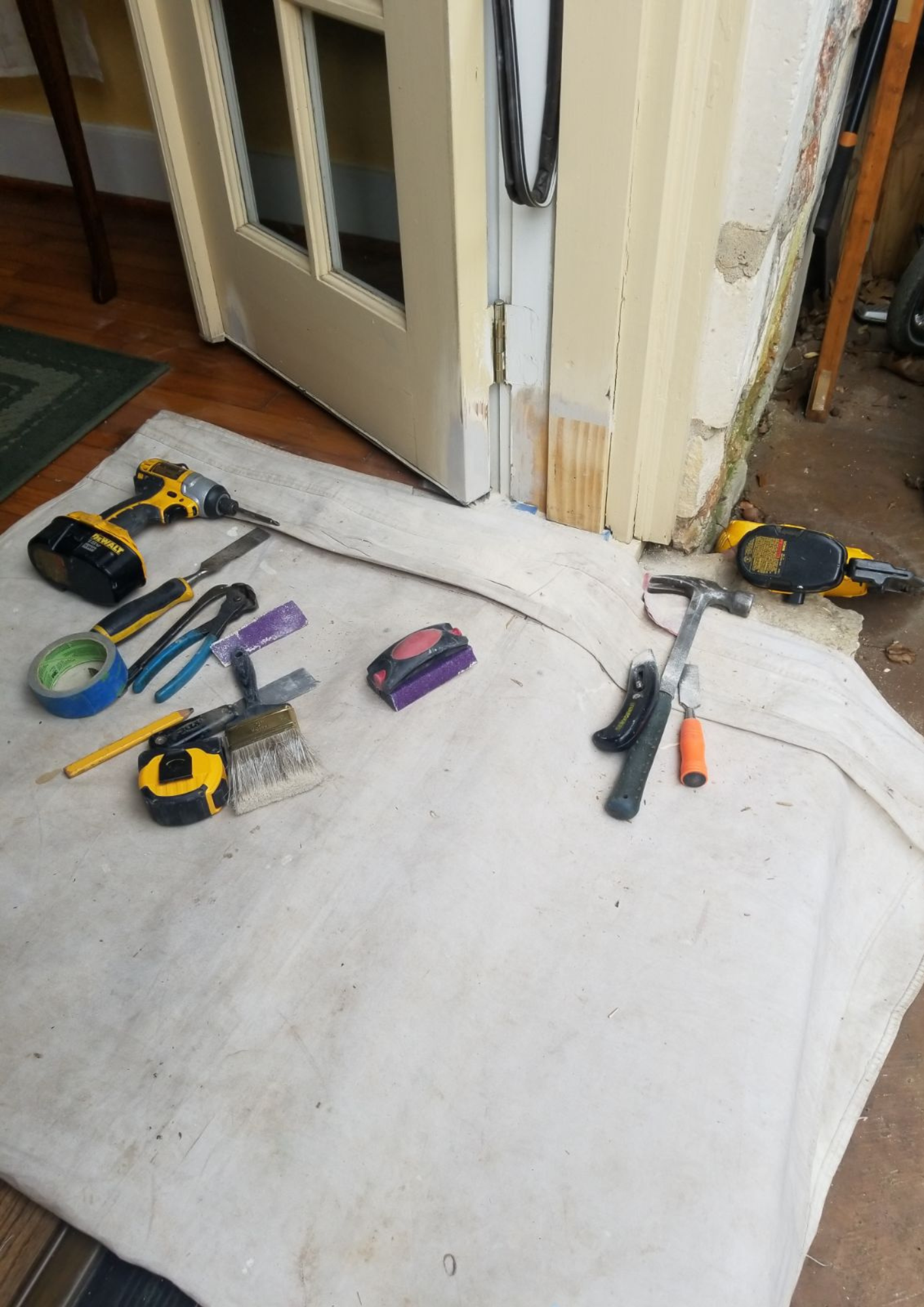 A bunch of tools are laying on the floor next to a door.