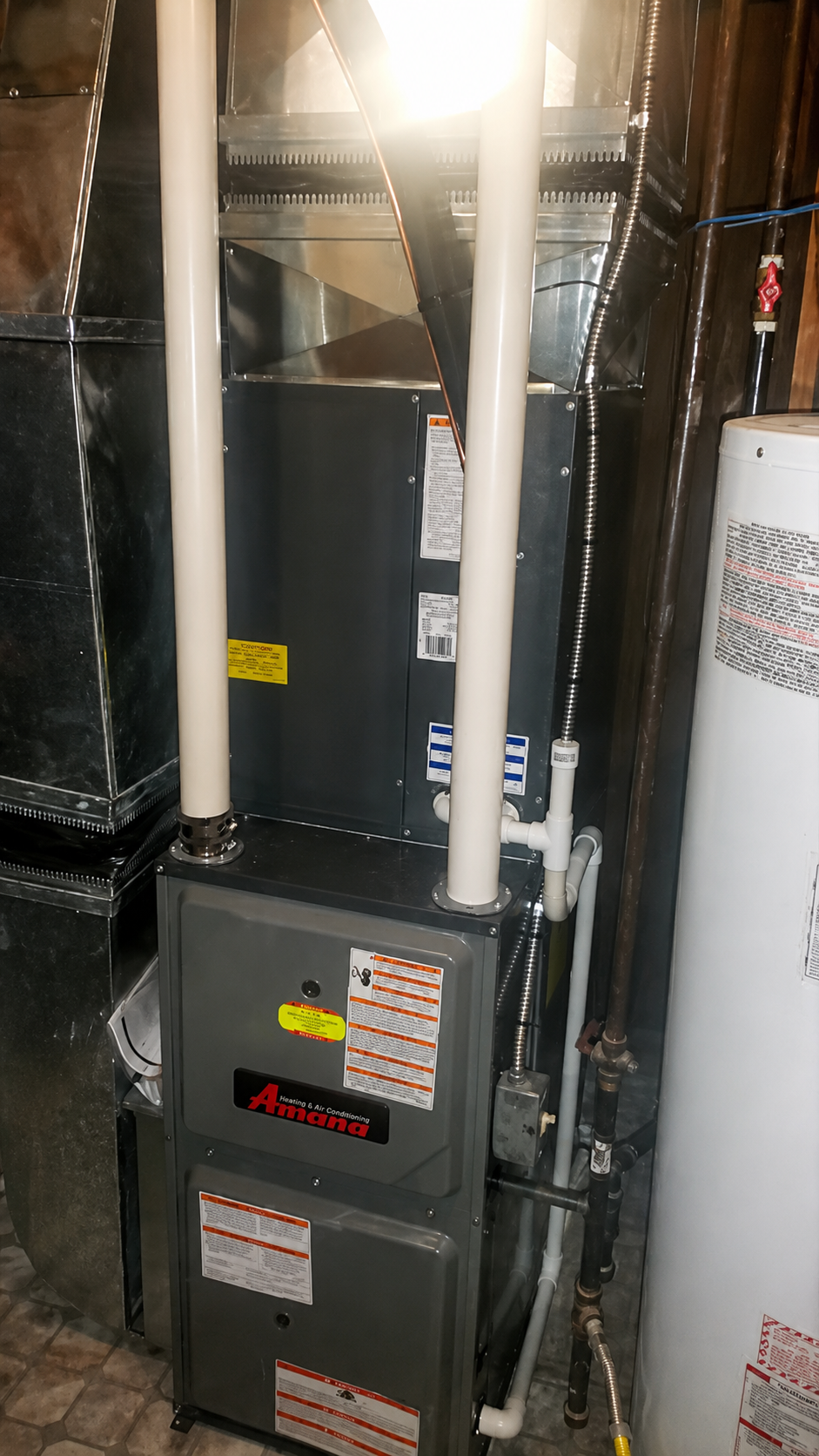 Basement furnace and HVAC unit with metal ductwork and pipes in a utility room