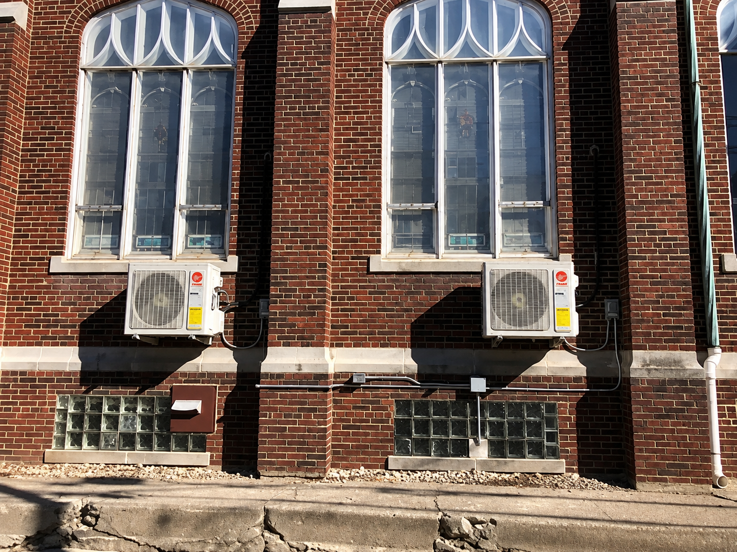 Brick building facade with two windows and window air conditioners beneath them