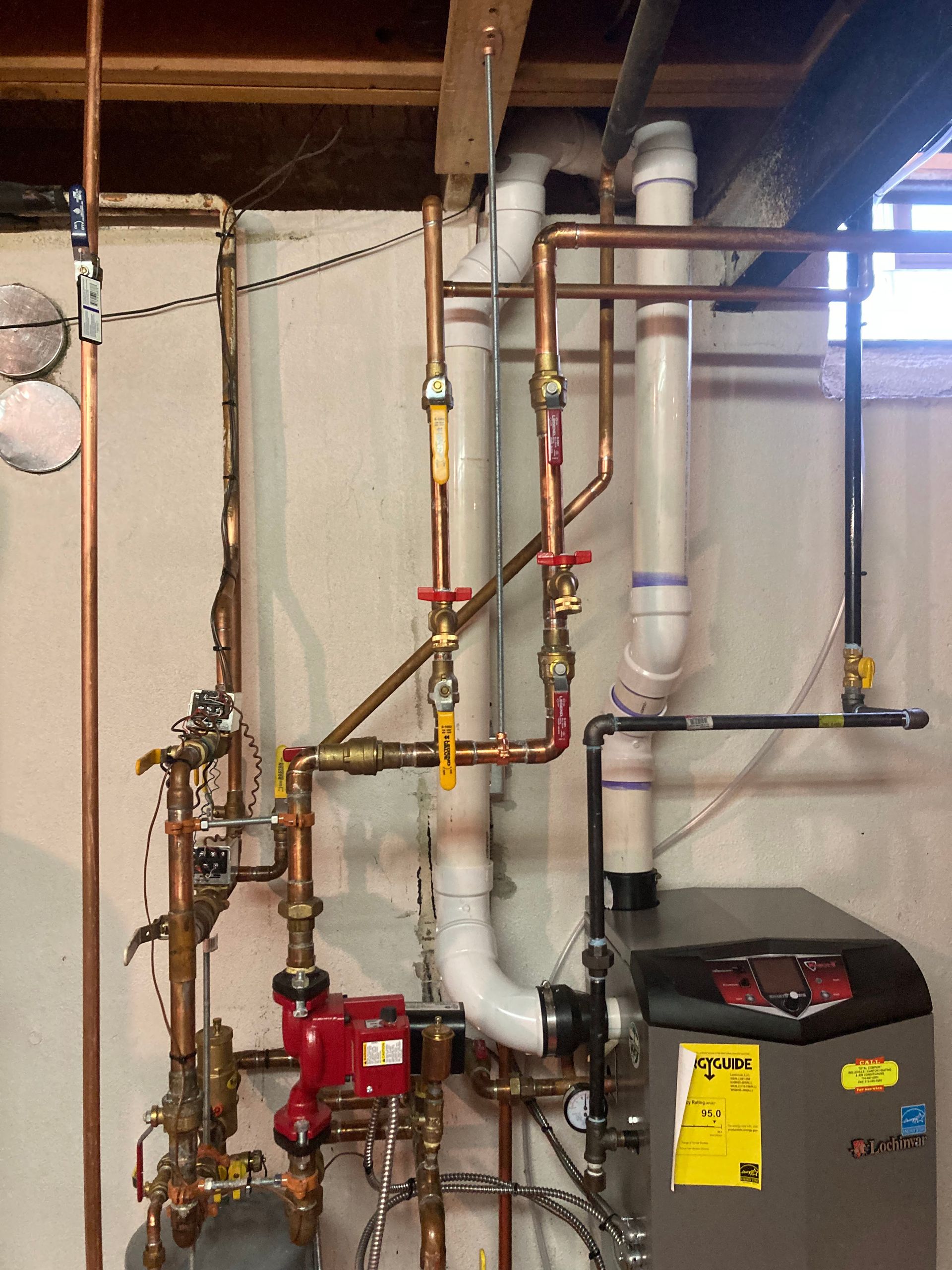 Basement utility room with copper pipes, water heater, boiler, and exposed ceiling joists.