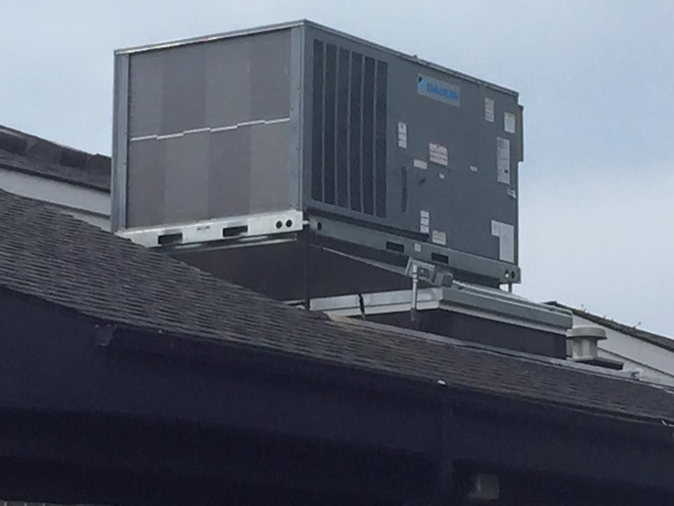 Large rooftop HVAC unit on a building roof against a cloudy sky