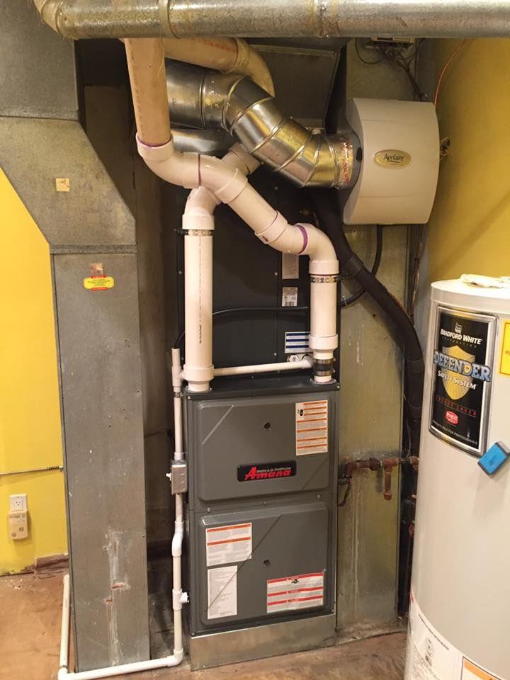 Furnace and water heater in a utility closet with white and metal ductwork and pipes.