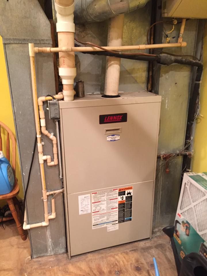 Gray furnace with visible piping in a utility room, surrounded by exposed insulation and concrete walls.