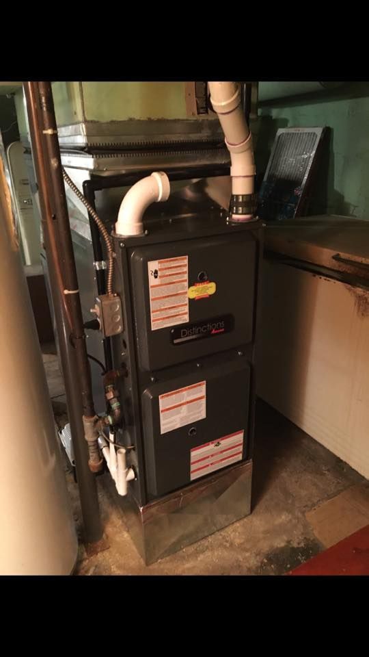 Gas furnace and ductwork in a utility closet with exposed piping.