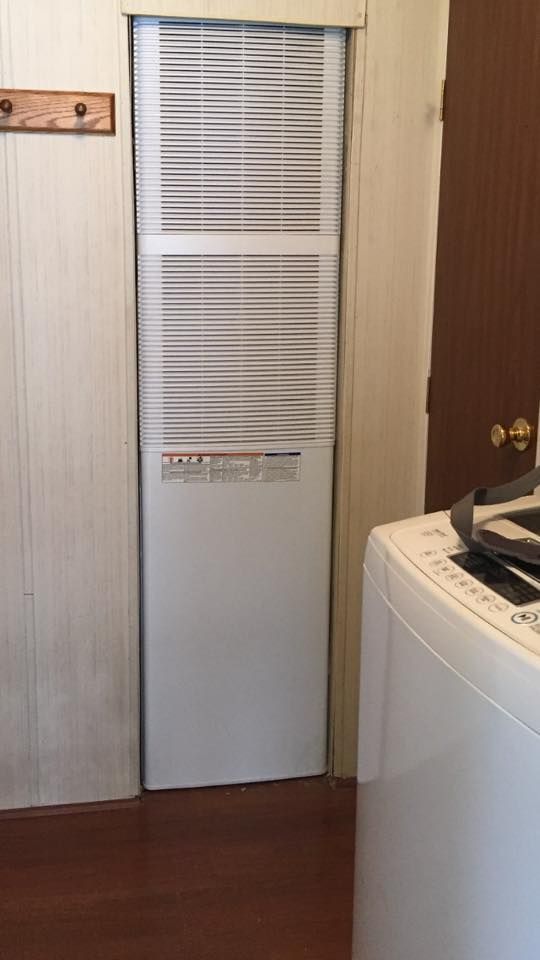 Narrow white closet door with slatted vent panels in a small laundry room beside a washing machine