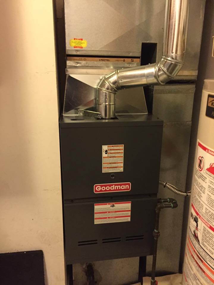 Goodman furnace with metal ductwork in a utility closet.