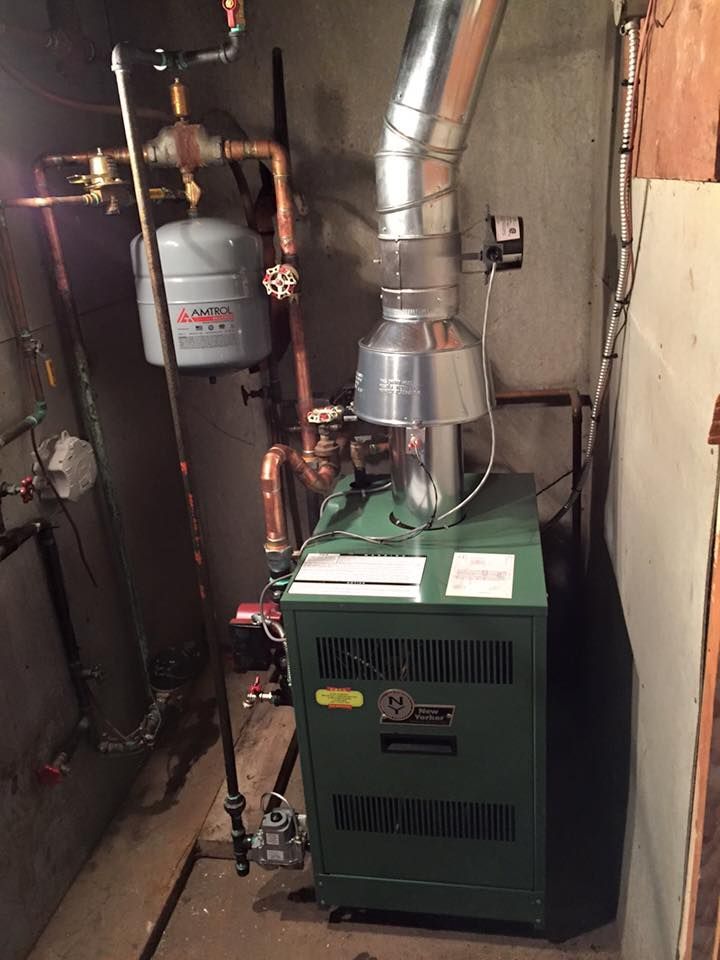 Basement furnace with metal venting, pipes, and a gray expansion tank beside it