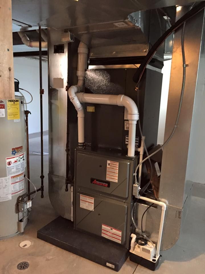 Furnace and ductwork in a utility closet, with white insulated pipes and metal panels.