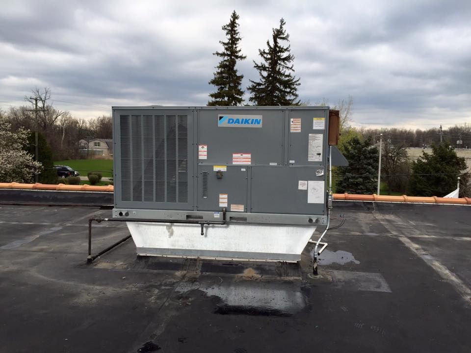 Large gray rooftop HVAC unit on a flat roof under a cloudy sky