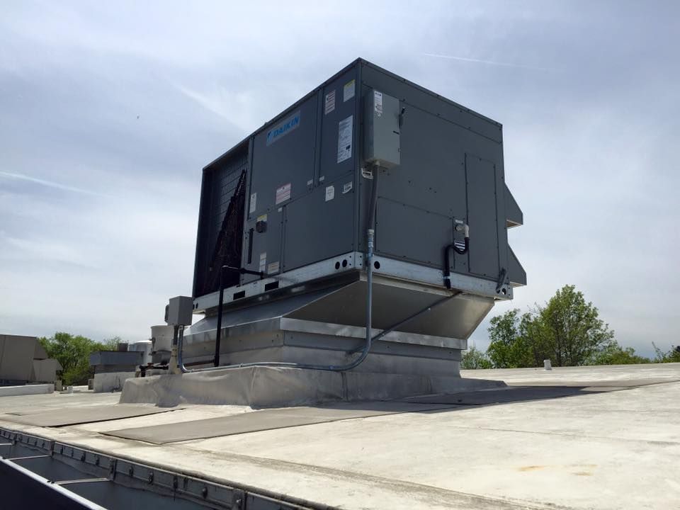 Large rooftop HVAC unit on a flat concrete roof under a cloudy sky
