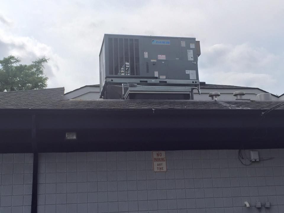 Rooftop HVAC unit on a gray building under a cloudy sky