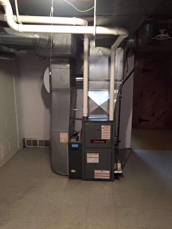 Furnace and HVAC ductwork in a basement utility room with exposed pipes and concrete walls