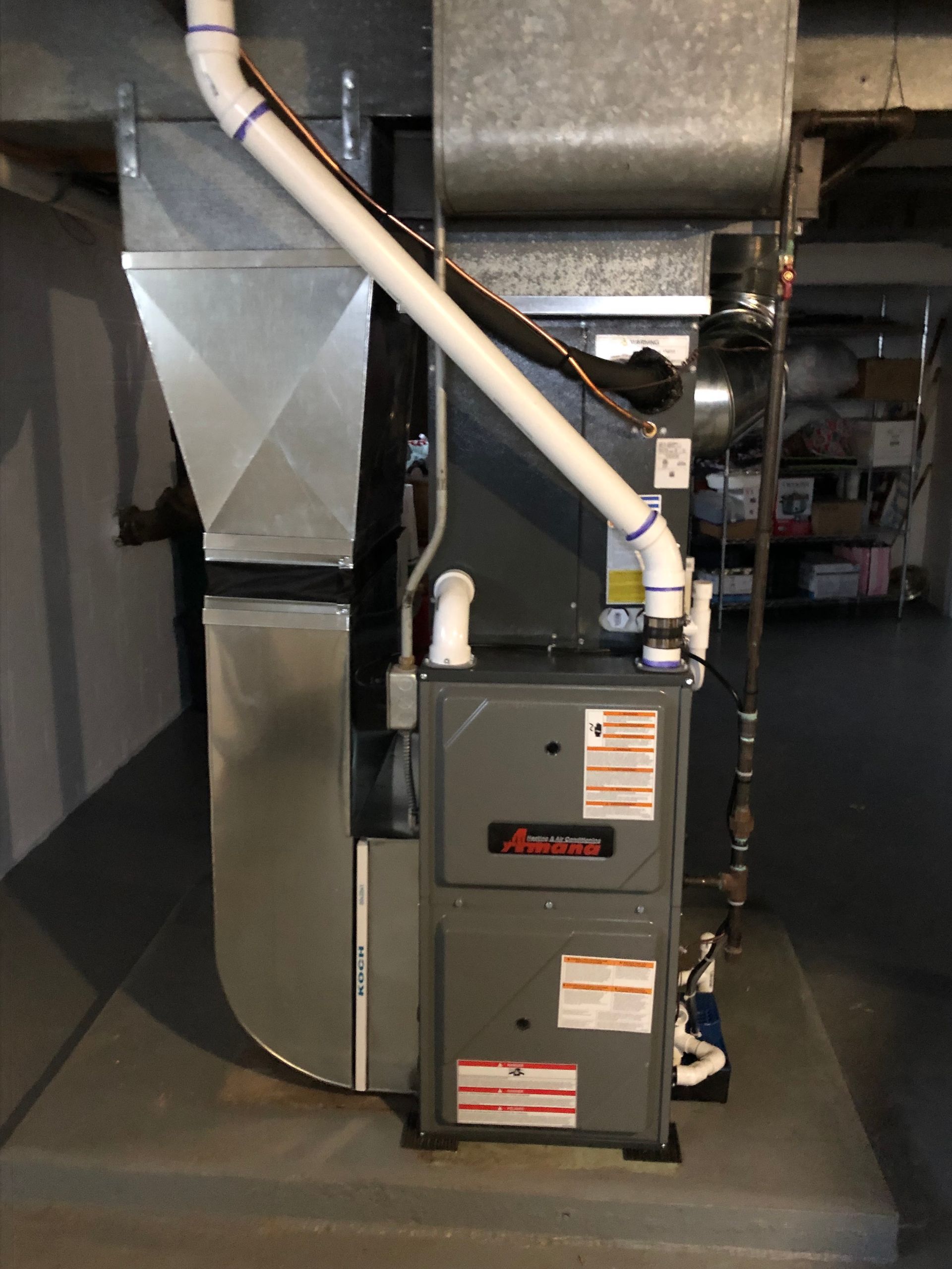 Basement HVAC furnace and ductwork with white vent pipe and gray metal unit