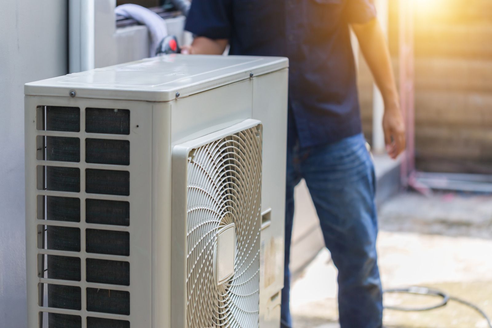 Outdoor air conditioning unit being serviced by a worker with a hose