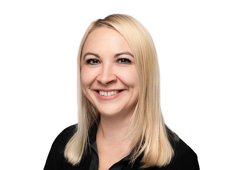 A woman with blonde hair is smiling and wearing a black shirt.