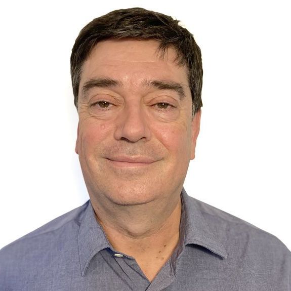 A man in a blue shirt is smiling for the camera