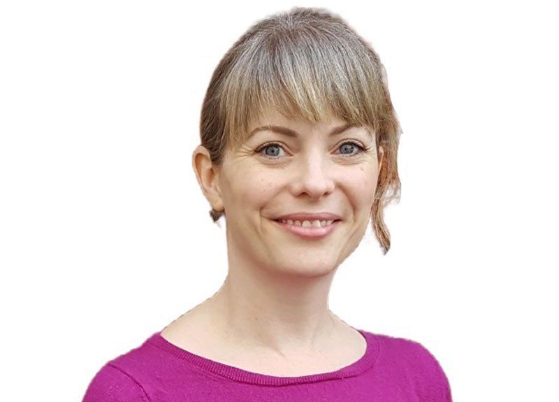 A woman in a purple shirt is smiling for the camera.