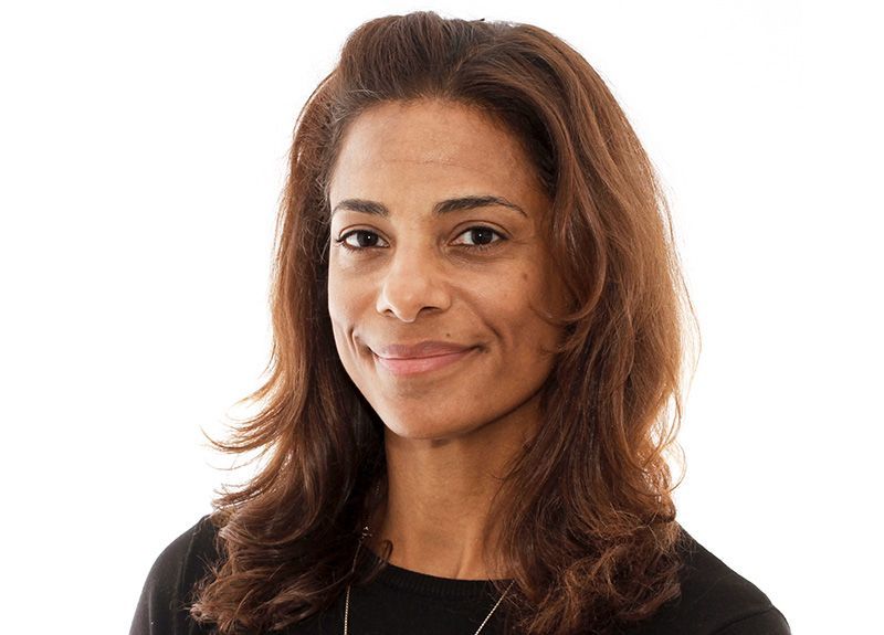 Portrait of a smiling woman with long brown hair against a white background