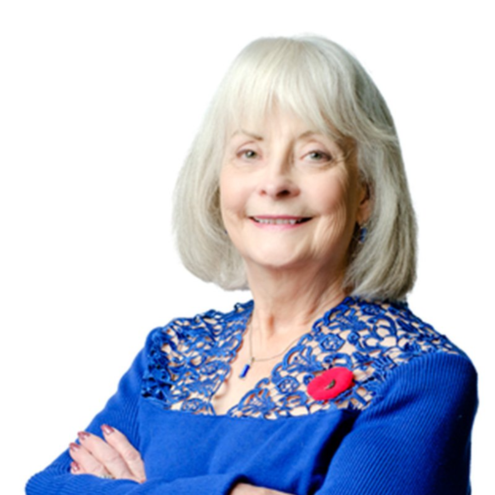 A woman in a  blue shirt is smiling for the camera.