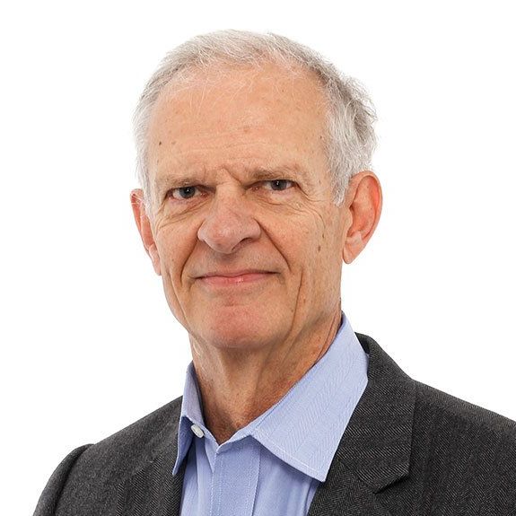 A man in a suit and blue shirt is smiling for the camera.