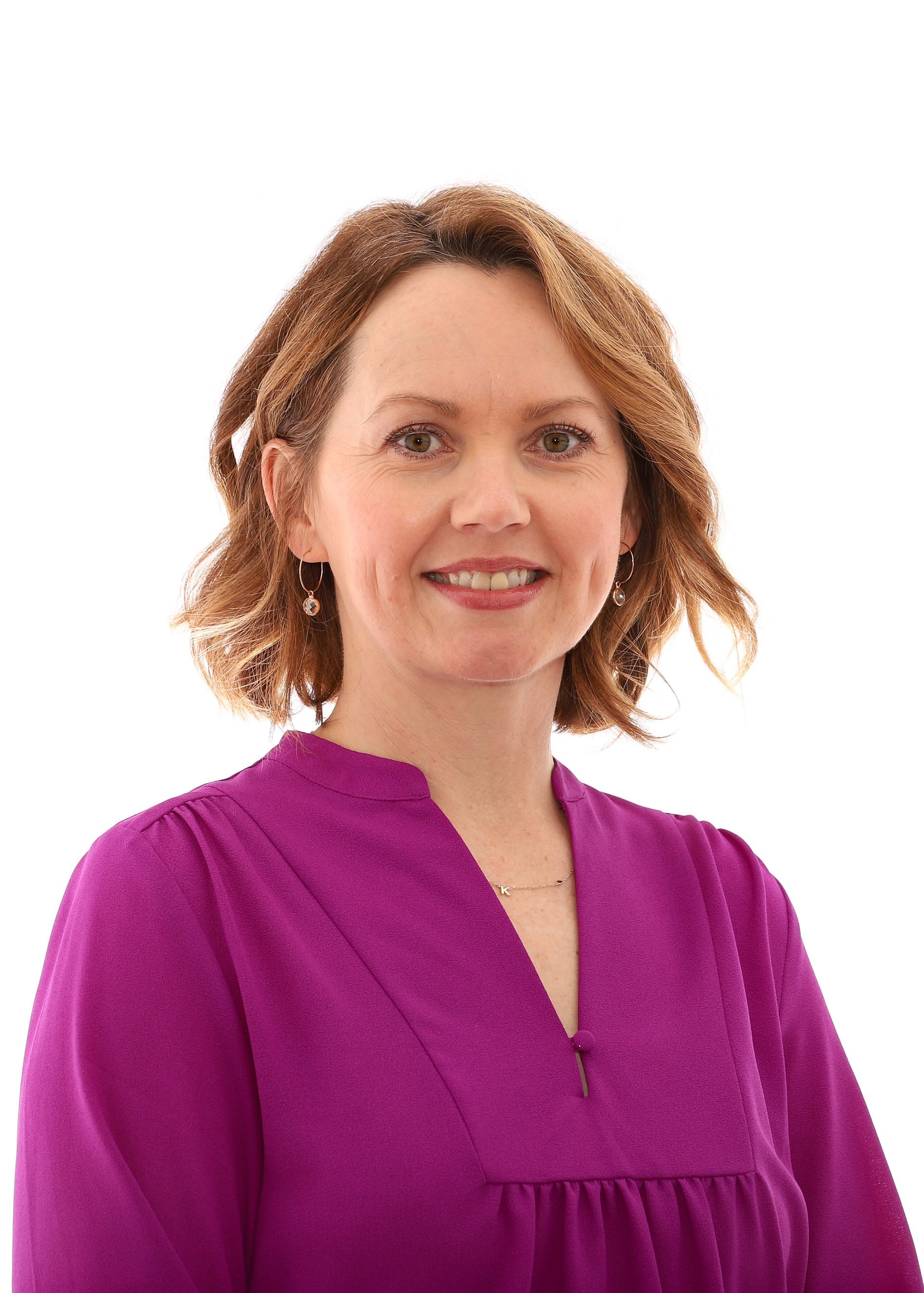 A woman in a purple shirt is smiling for the camera.
